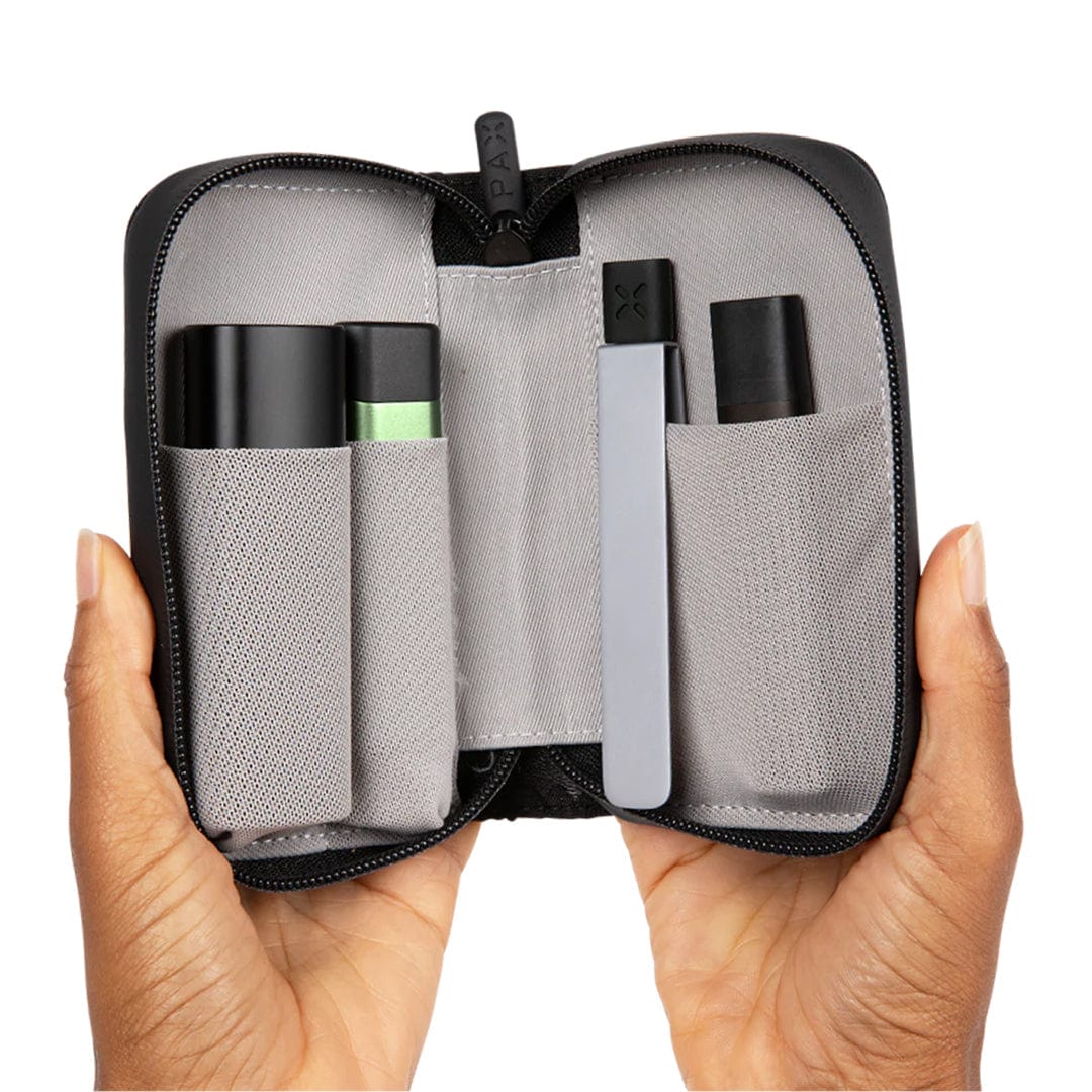 A pair of hands holds open the PAX Smell Proof Bags, revealing two cylindrical black containers inside the zippered pouch.