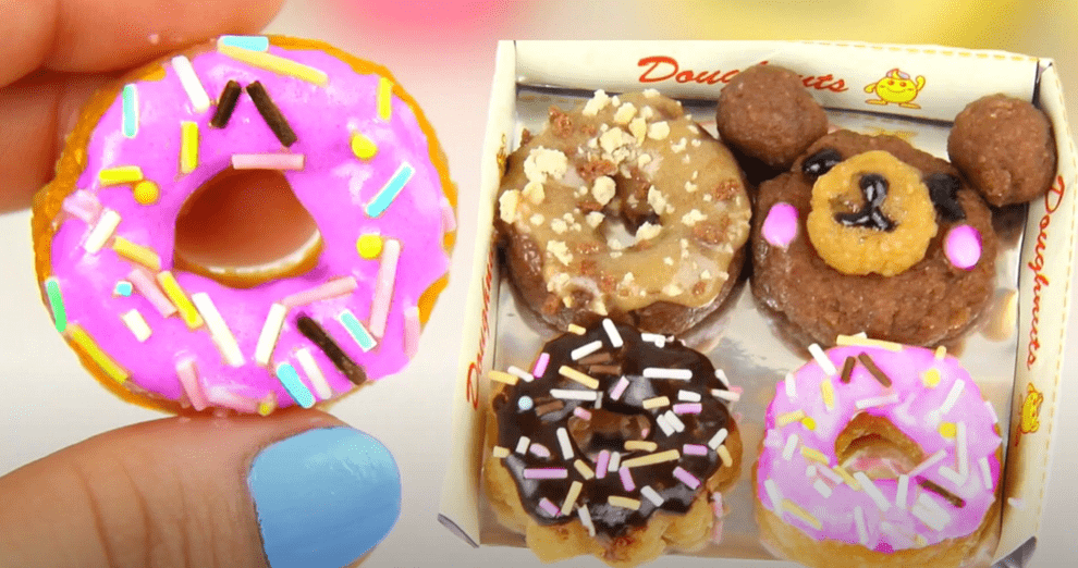 Close-up, overhead view of colorful, miniature donuts created with the Kracie Popin Cookin DIY Candy Making Kit, arranged in a small cardboard box.