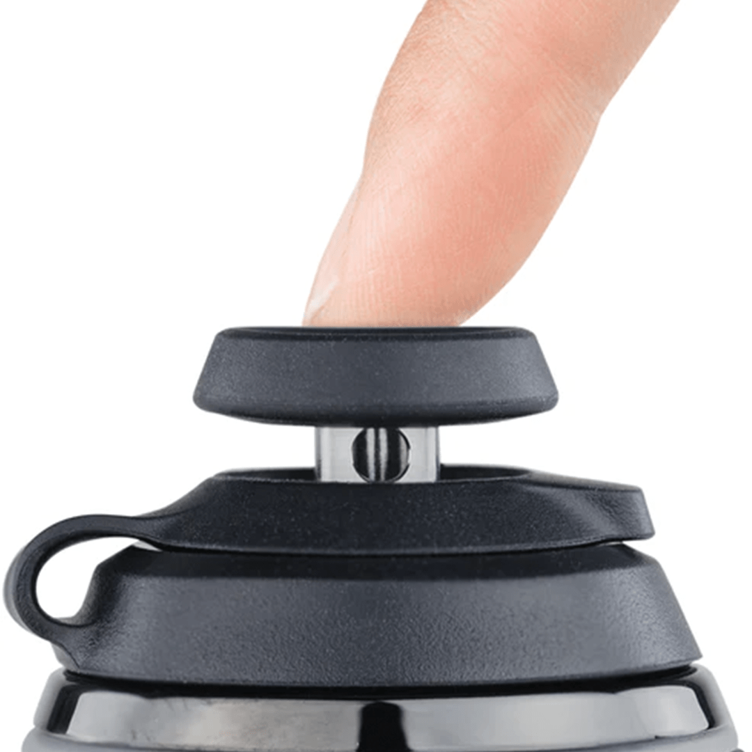 Close-up of a finger pressing the black Puffco Proxy Carb Caps Desert-style carb cap seated on a metal post against a white background