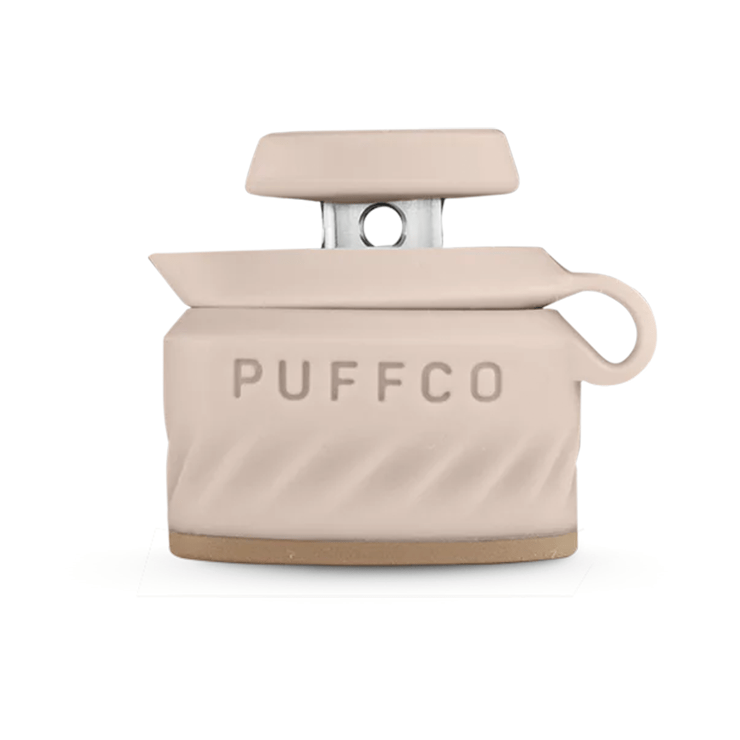 Center-frontal view of a pale pink Puffco Peak Pro Joystick Cap with raised PUFFCO logo, textured base and small loop handle against a white background