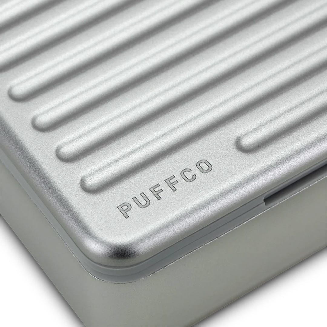 Close-up angled view of the silver Puffco Pivot Travel Case lid with ribbed texture and embossed PUFFCO logo.