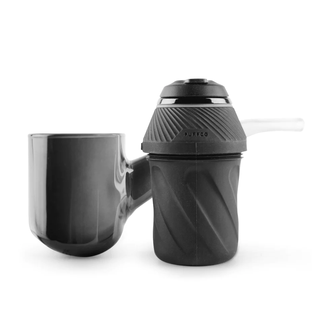Front-facing studio shot of the black Puffco Proxy showing its textured chamber, attached glossy glass water cup to the left, and short glass mouthpiece to the right