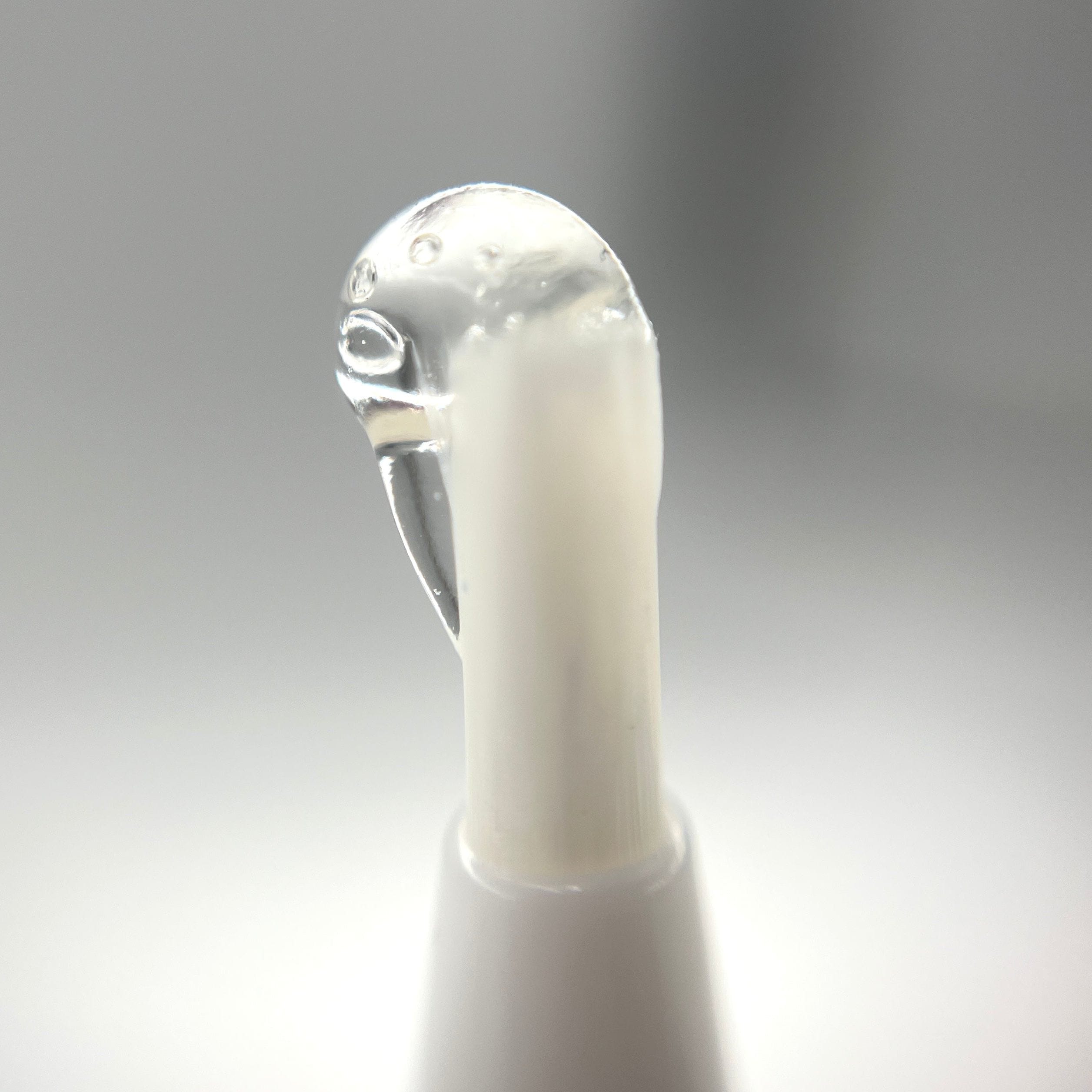 Close-up of a clear glossy drop on the applicator tip of Cannagar & Blunt Rolling Glue - 4ml against a soft grey background