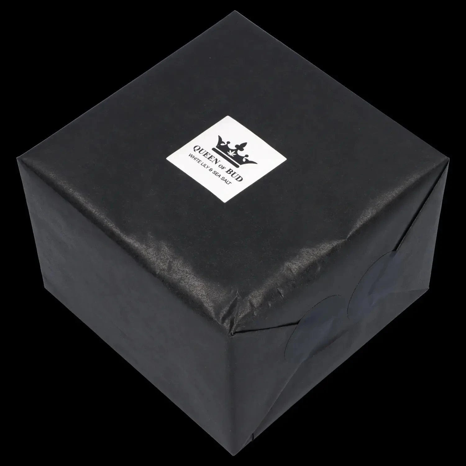 Angled top-down view of a black-wrapped box with a centered white label reading "Queen of Bud Candle."