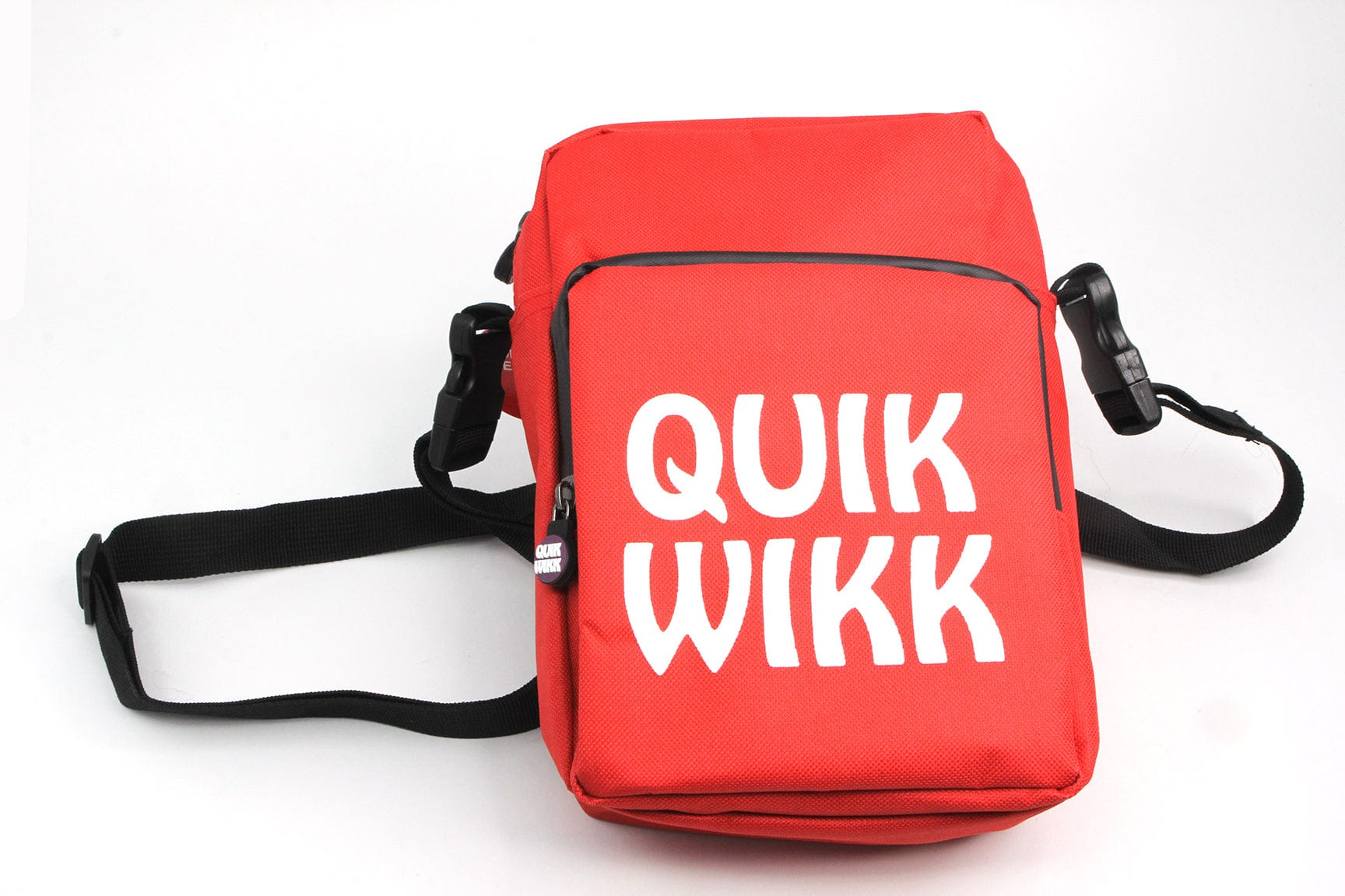 Front-facing shot of a red Quik Wikk Shoulder Cross Body Bag lying on a white background, showing its black strap, buckles, and bold white logo.