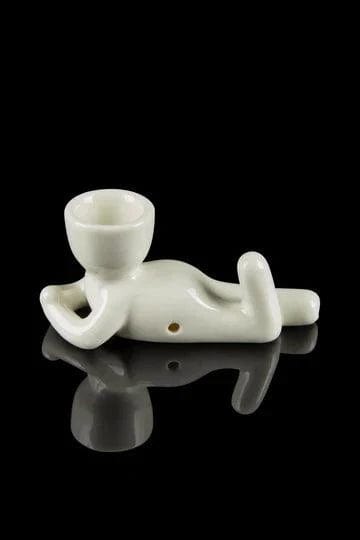 A studio shot of the “Pot Head Pipe” ceramic pipe in the shape of a head, resting on a reflective surface.