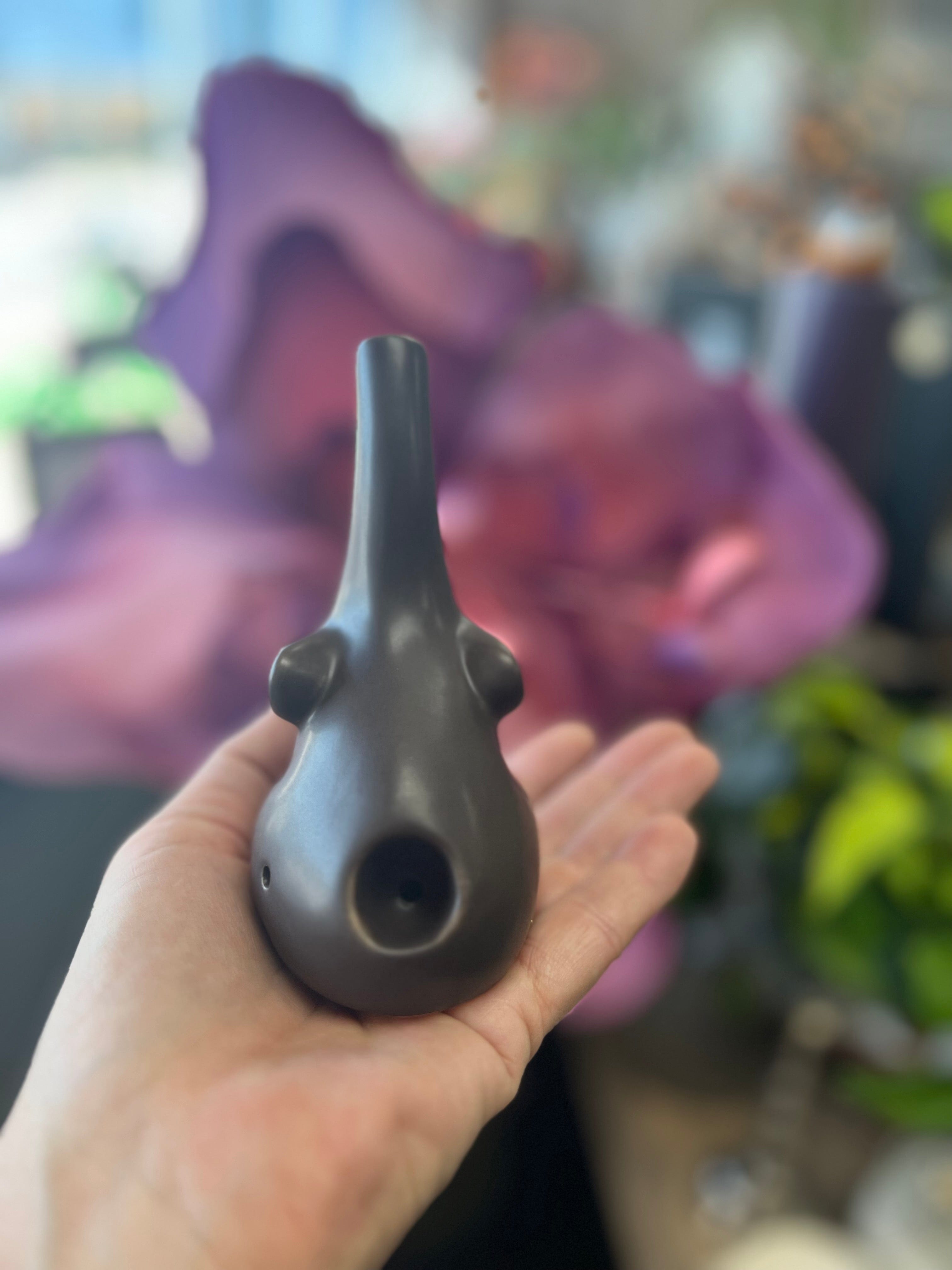 A hand holds the small Baby Elephant Sherlock Pipe, its dark finish contrasting with a blurred purple backdrop.