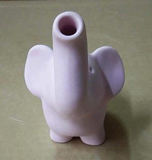 The Elephant Pipe is shown in a side view against a solid green background, highlighting its smooth, sculpted form.