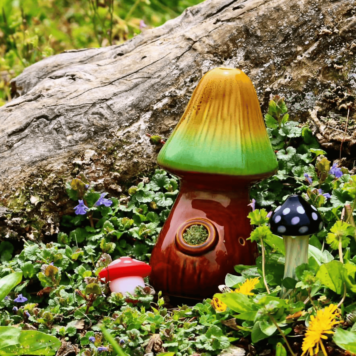A side view of the Mushroom Pipe resting amongst green foliage and wildflowers on a textured wooden surface.