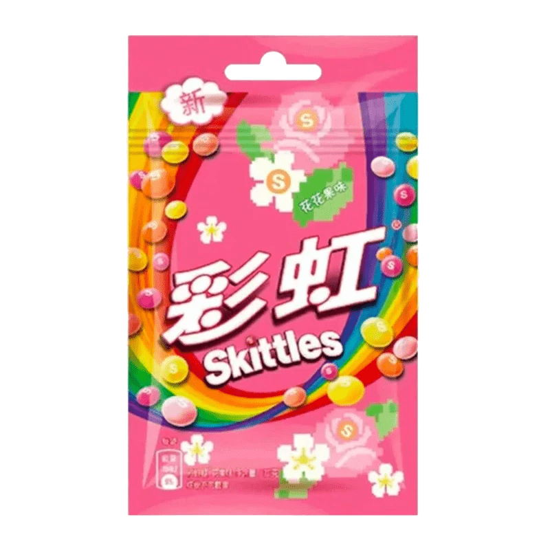 A front view of Skittles - Floral Fruit Candy packaging with a bright pink floral pattern and scattered candy pieces.