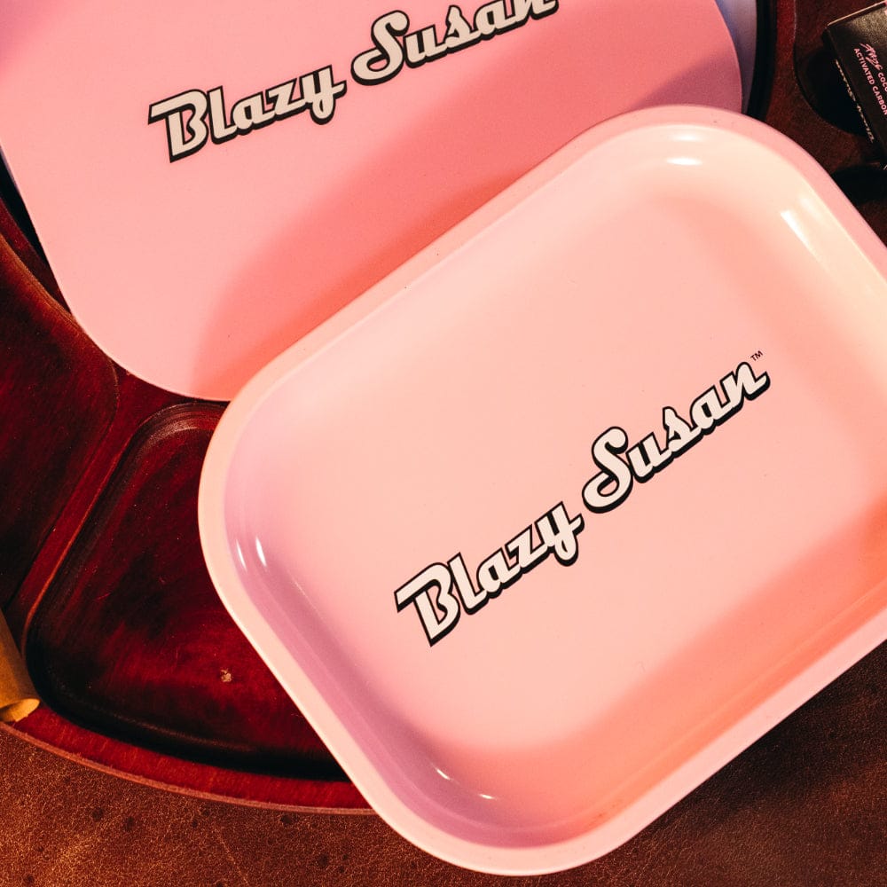 Top-down view of a small pink Blazy Susan Metal Rolling Tray with its lid nearby, both stamped with the Blazy Susan logo.