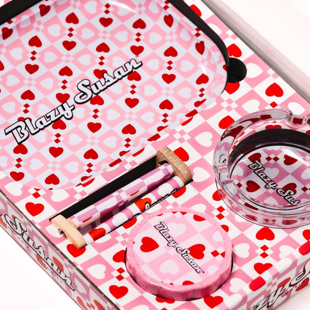 Top-down view of the Carbon Black Blazy Smoker's Kit open to show patterned pink and red heart-checked tray, glass ashtray, and rolling papers.