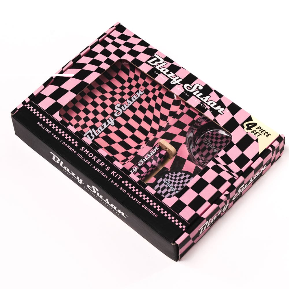 Angled top-down view of the pink-and-black checkered Blazy Smoker's Kit box with a window revealing matching tray, grinder, and accessories.