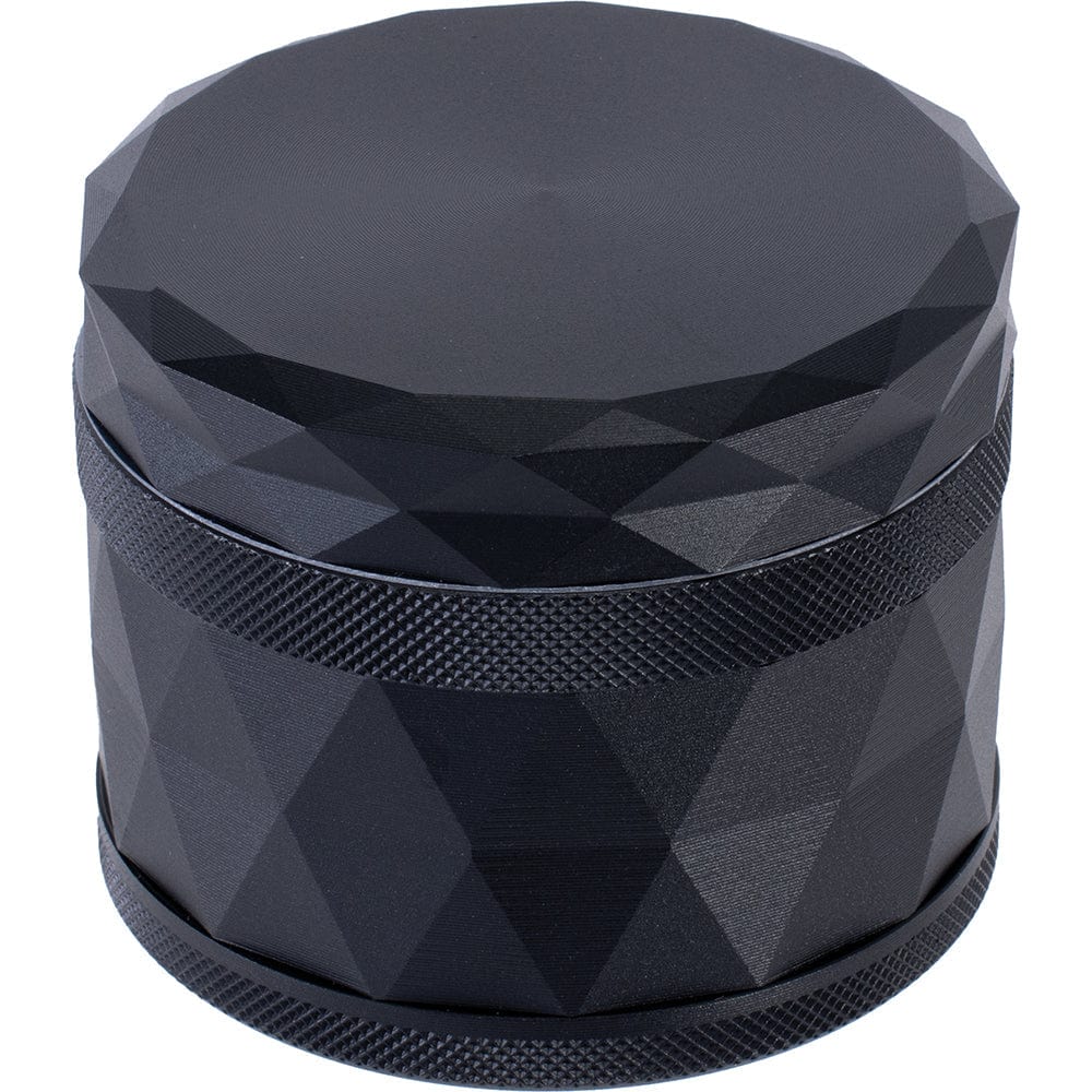 A close-up, angled view of the Four Piece Grinder, featuring a textured, dark-colored metallic surface.