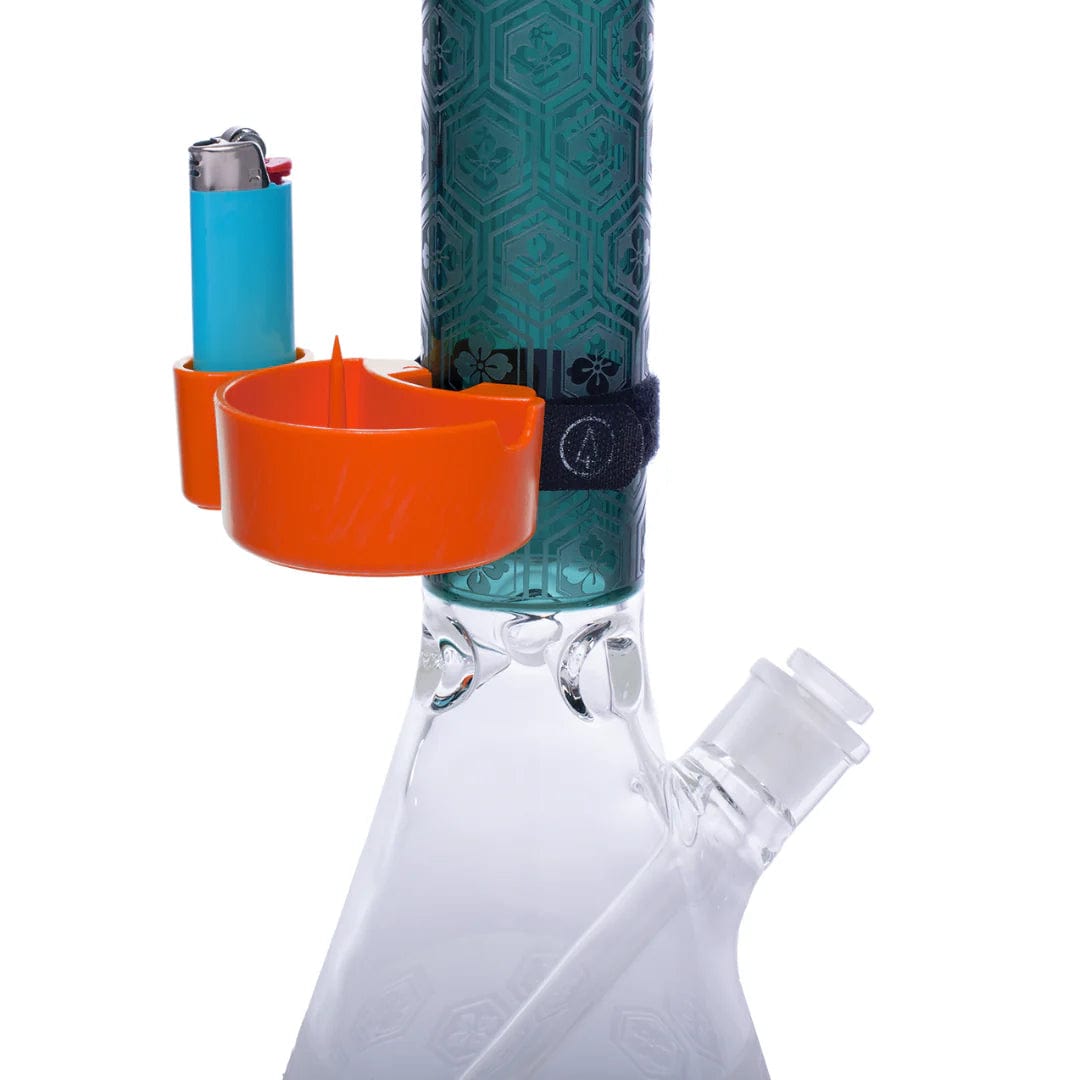 A close-up view of the TreeHouse AshTray, an orange silicone catch-all attached to a patterned glass piece with a blue lighter beside it.