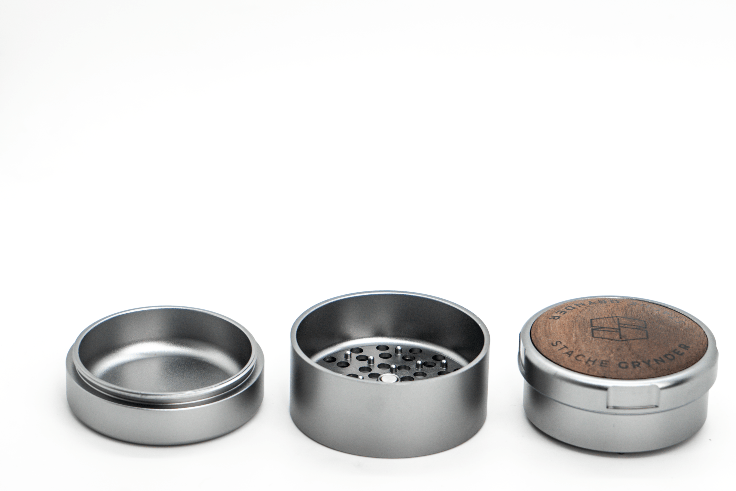 A close-up, angled view of the three-piece Grynder (N.Y.A.G) grinder, showing its silver metal construction and segmented design.