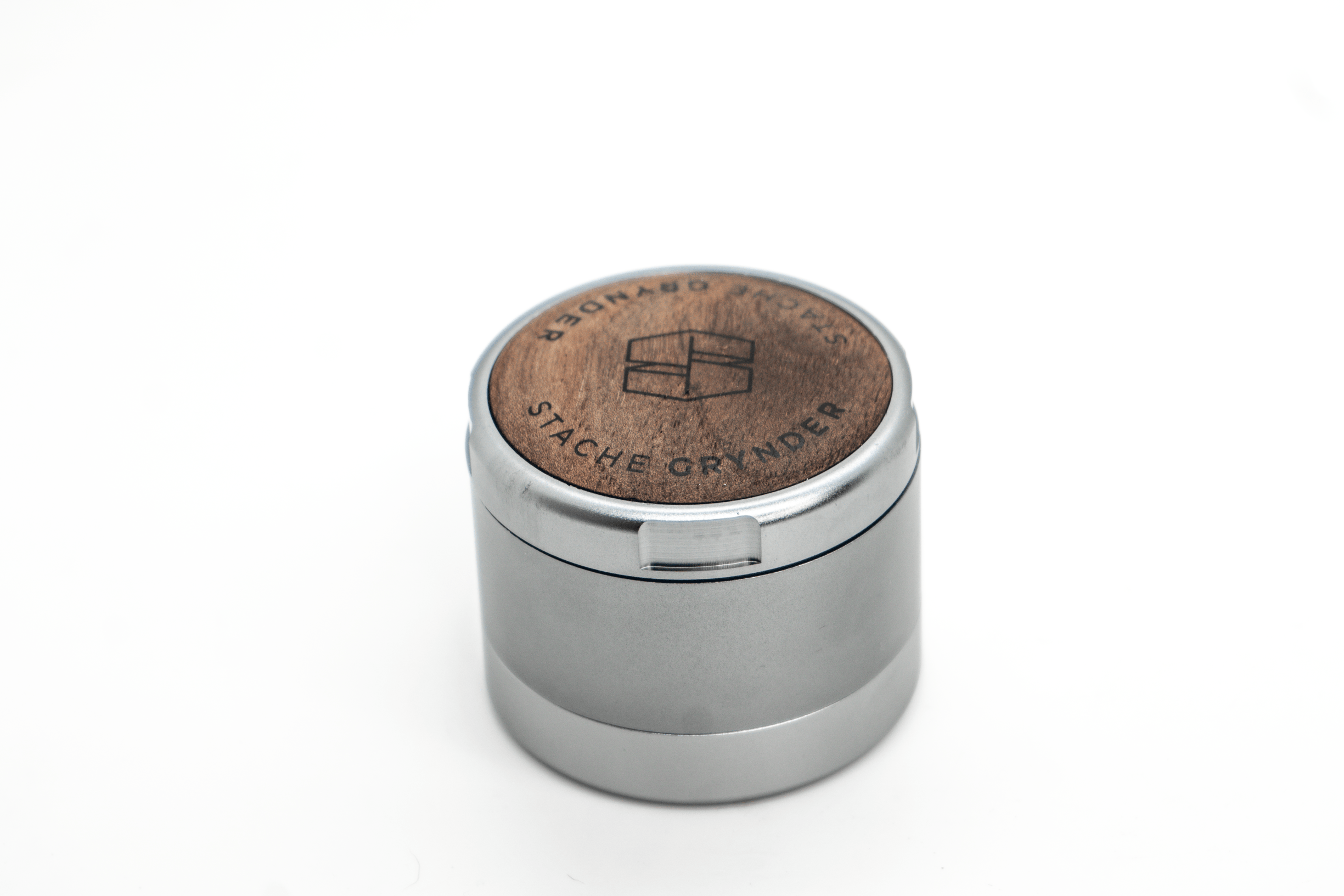 Close-up, angled view of the 3-Piece Grynder (N.Y.A.G) aluminum grinder, reflecting light on a plain white surface.
