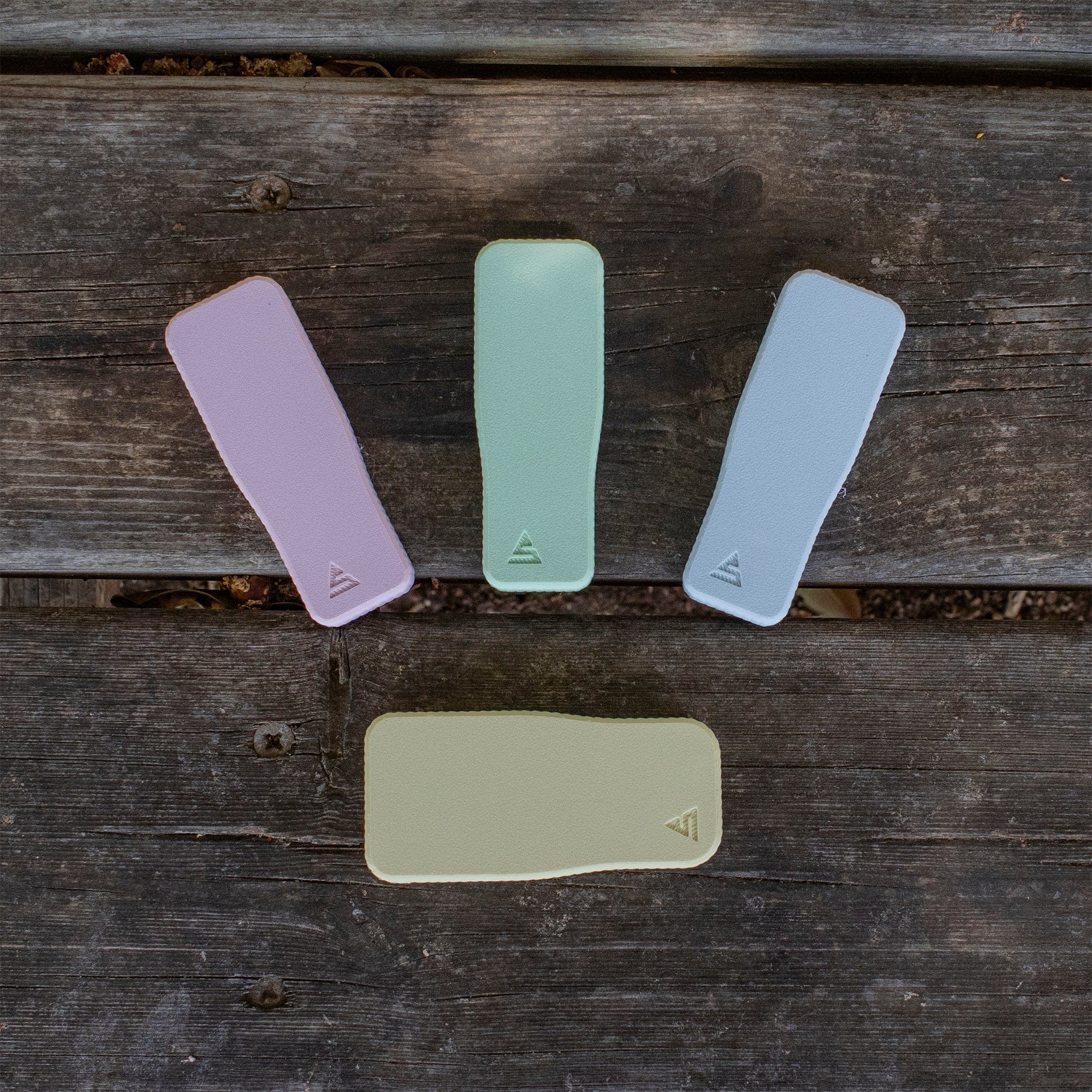 Top-down view of three pastel STASURE Joint Case Pastel Polar Blue pads fanned on a weathered wooden bench.