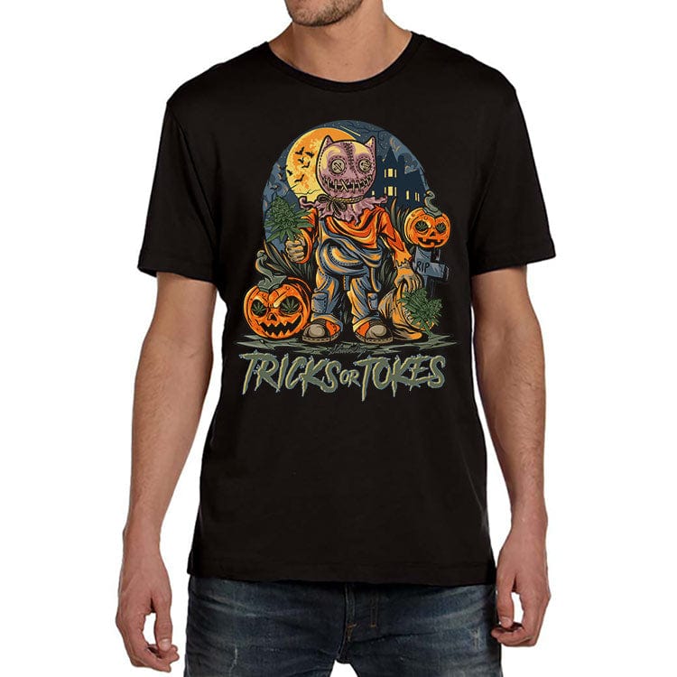 Front view of a man wearing a black Trick or Tokes Tee featuring a colorful Halloween character holding pumpkins and standing before a moonlit graveyard.