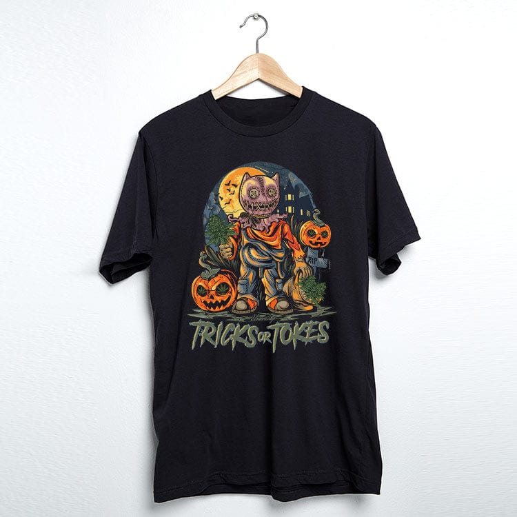 Front-facing view of a black Trick or Tokes Tee hanging on a wooden hanger, lit evenly to show a colorful Halloween graphic with pumpkins, a masked figure, and a moonlit background.