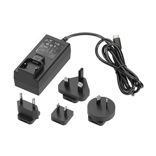 A slightly angled, overhead shot of the Venty / Mighty+ Super Charger and various international plug adapters arranged neatly on a white surface.