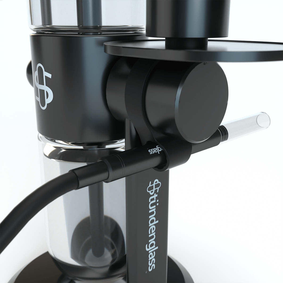 Close-up angled view of the black Hose Clip - Black attached to a matte black stündenglass rig, showing the clip holding a clear glass mouthpiece and a black hose connection.
