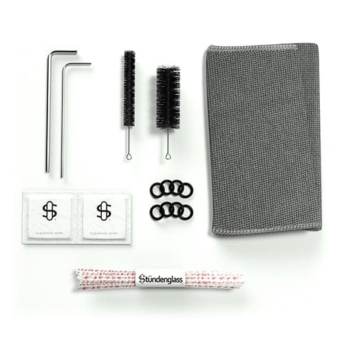 Top-down view of Cookies x Stündenglass Gravity Infuser accessory kit laid out on white background, showing two hex keys, two cleaning brushes, a gray cloth, O-rings, wipes, and branded pipe cleaners.