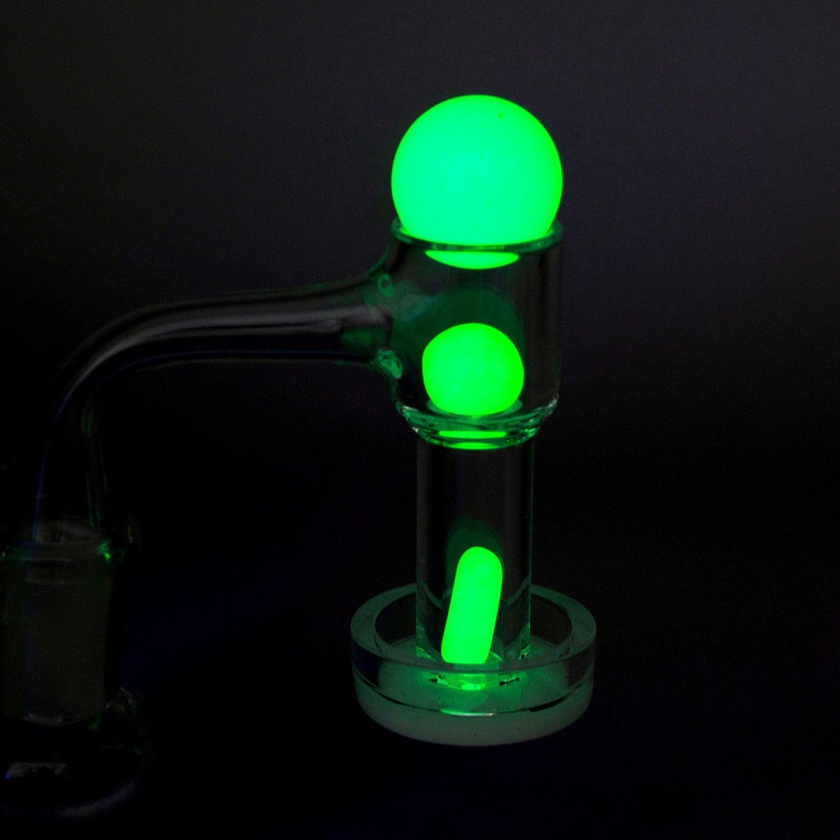 A close-up, angled view of the Glow in The Dark Glass Terp Slurper Set, illuminated with a vibrant green glow against a dark background.