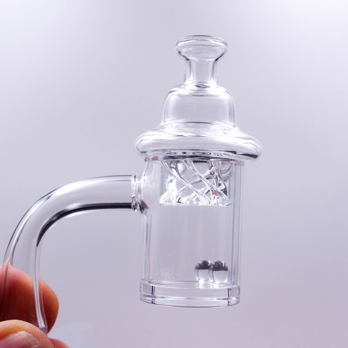 A close-up, angled view of the Quartz Banger Set with Spinning Carb Cap and Terp Pearls, showing the clear quartz and spinning pearls inside.