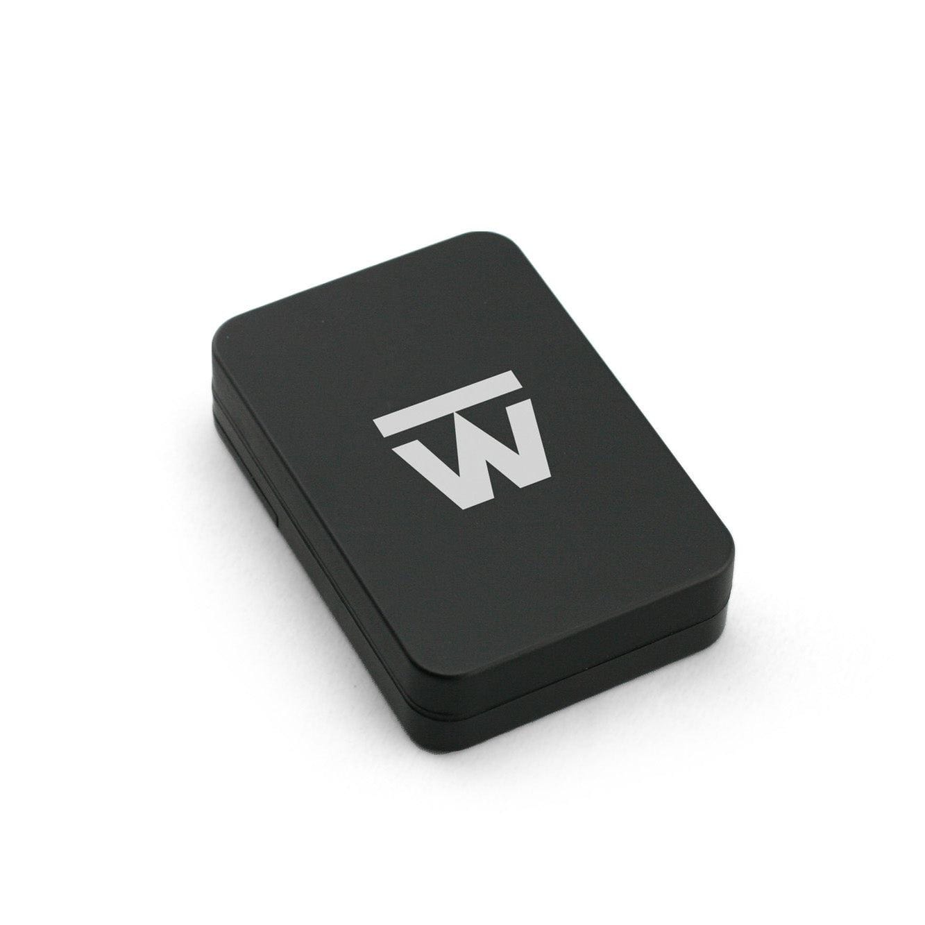 Angled top-down view of a compact black Gauge Scale | 100g x 0.01g case with a white stylized "W" logo on a white background.
