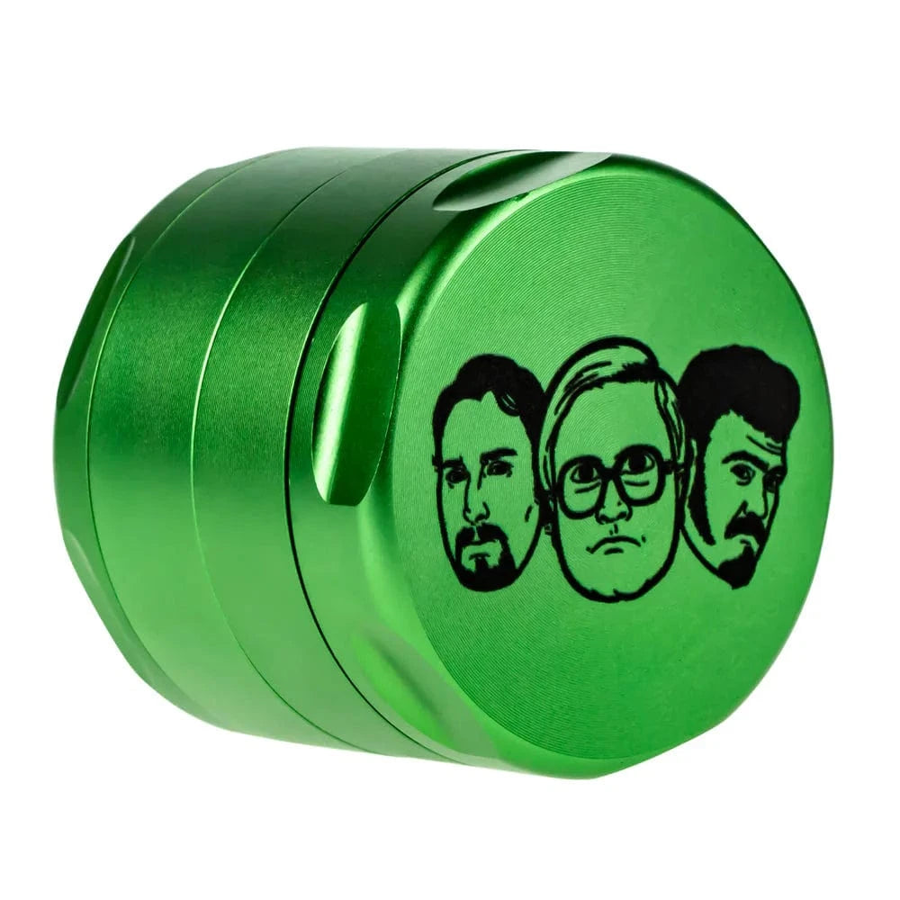 Angled close-up of a green Famous X Trailer Park Boys Grinder - Assorted Colors showing three black sketched faces on the lid.
