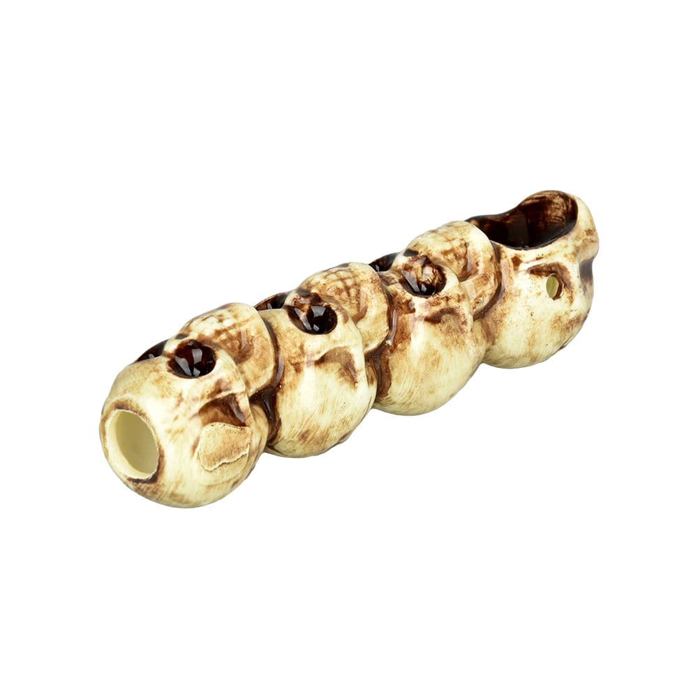 A detailed close-up of the "4" Skulls Ceramic Hand Pipe, showing four sculpted skulls along the pipe's body.