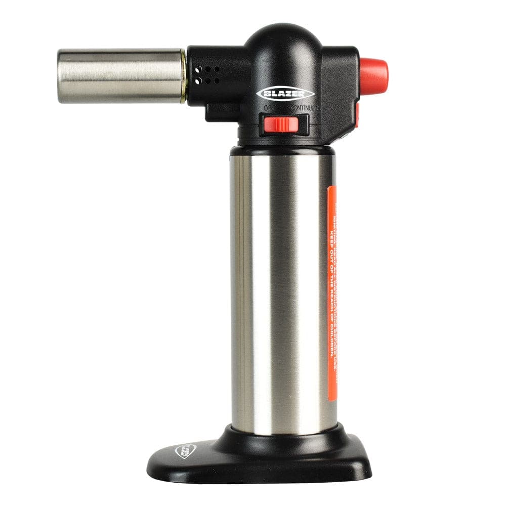 A close-up shows the silver Blazer Big Buddy Torch Lighter with a black grip, angled slightly against a white background.