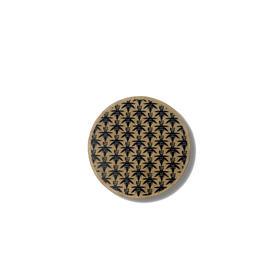 Top-down view of The Bzz Grinder, a metallic grinder with a circular design and textured surface.