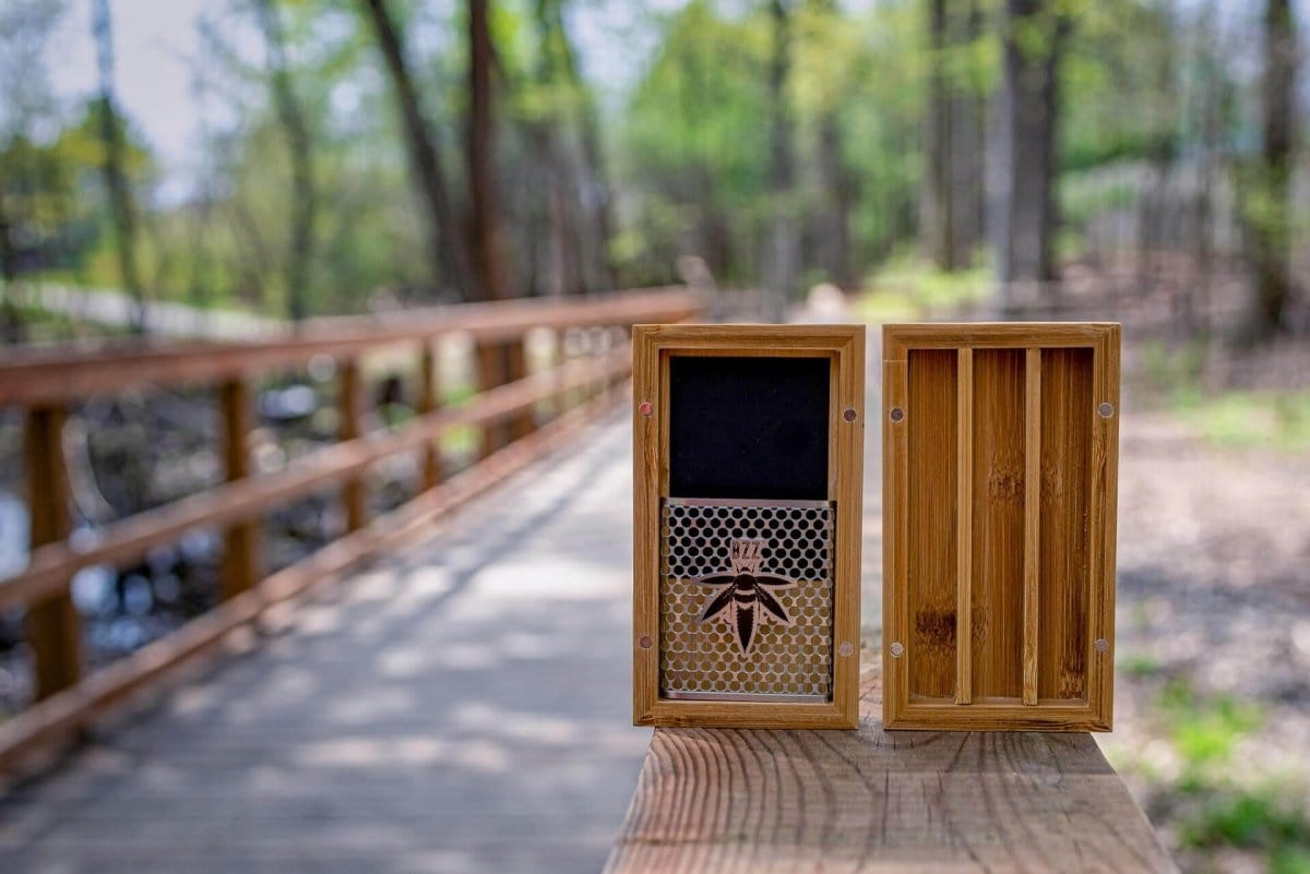 Front view of the Bzz Ritual (Bzz Mini) on a wooden surface, set against a blurred outdoor background.