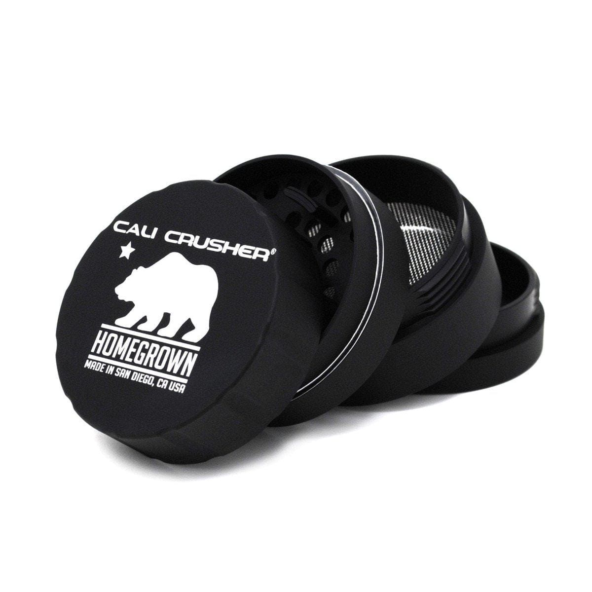 Front view of the Cali Crusher Homegrown Grinder 4pc, a dark-colored grinder with a reflective metal logo on a plain background.