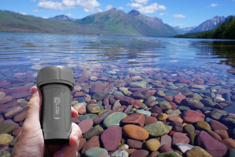 A close-up shows the Zytel Gray Premium 120CC Storage Canister with a black cap, positioned against a blurry backdrop of rocks and water.