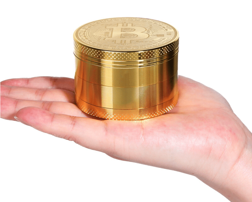 A hand holds the 4 Piece Small Bitcoin Metal Grinder, showcasing its metallic finish and compact, multi-part design.