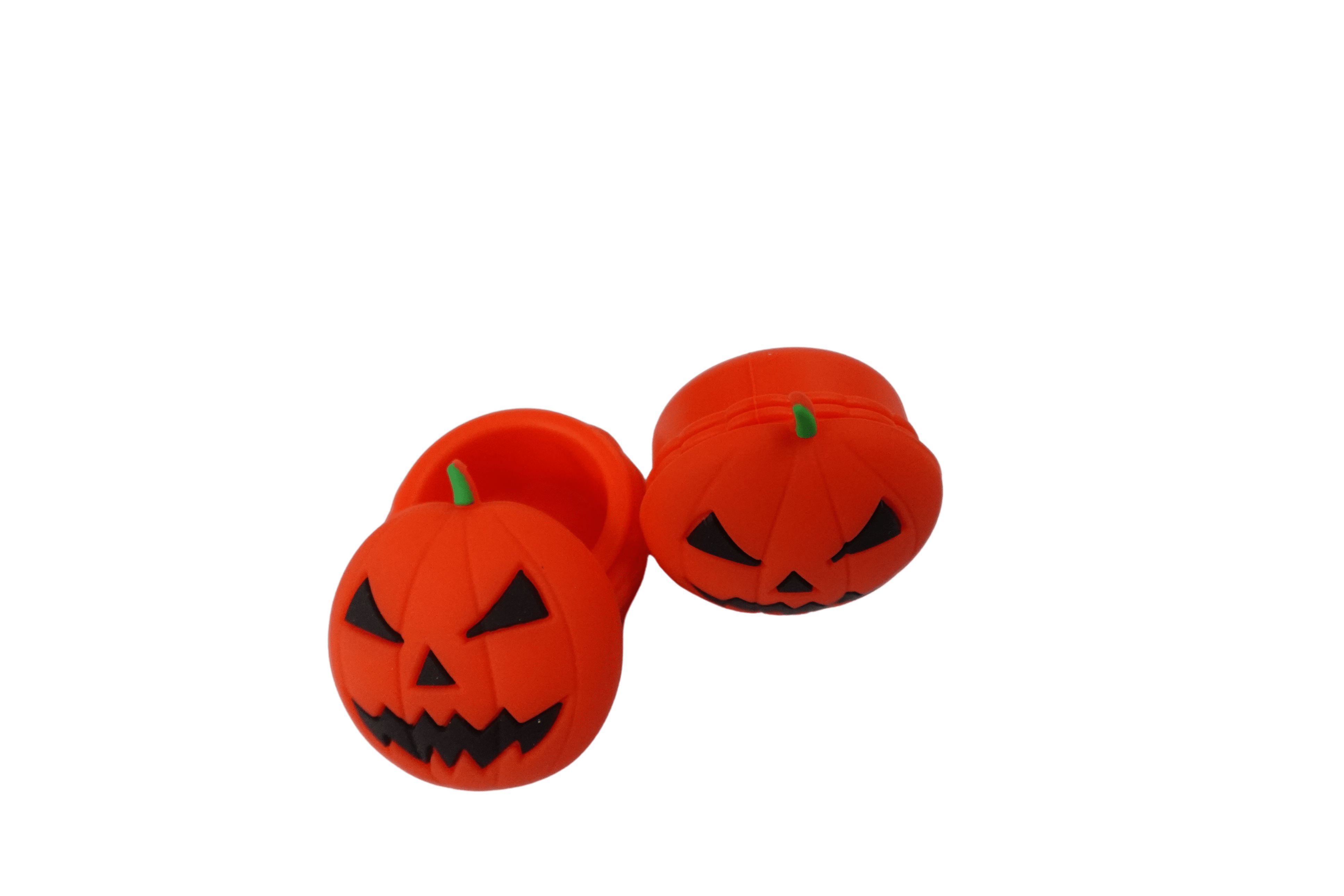 Close-up, low-angle view of three orange 15 ml Pumpkin Silicone Wax Oil Concentrate Vaporizer Cream Container pumpkins with carved jack‑o'‑lantern faces on a black background.