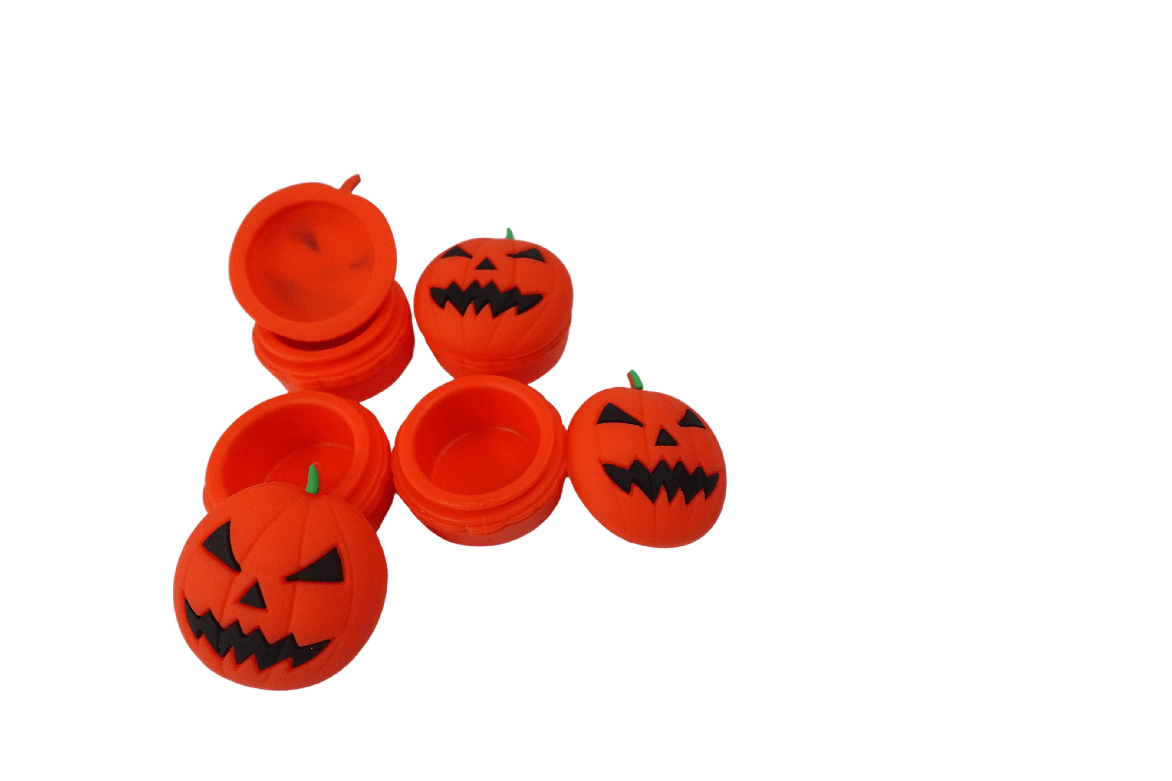 Close-up front view of several bright orange 15 ml Pumpkin Silicone Wax Oil Concentrate Vaporizer Cream Container jack-o'-lantern pieces on a black background