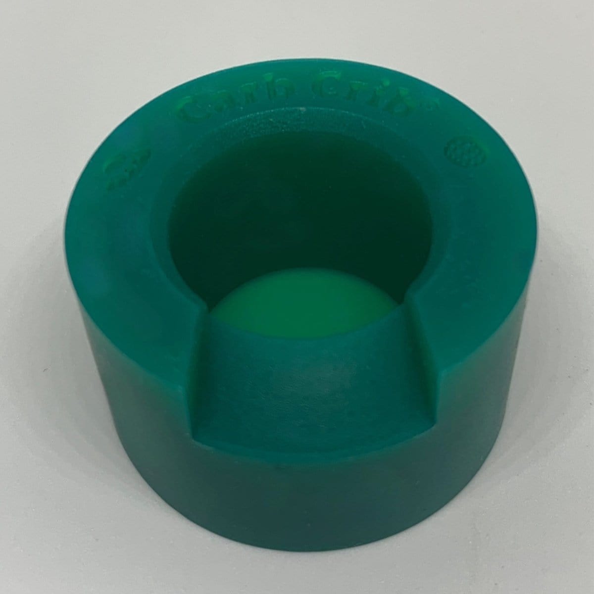 Front view of the V2 Carb Crib®, showing a rounded, dark-colored object against a bright white background.