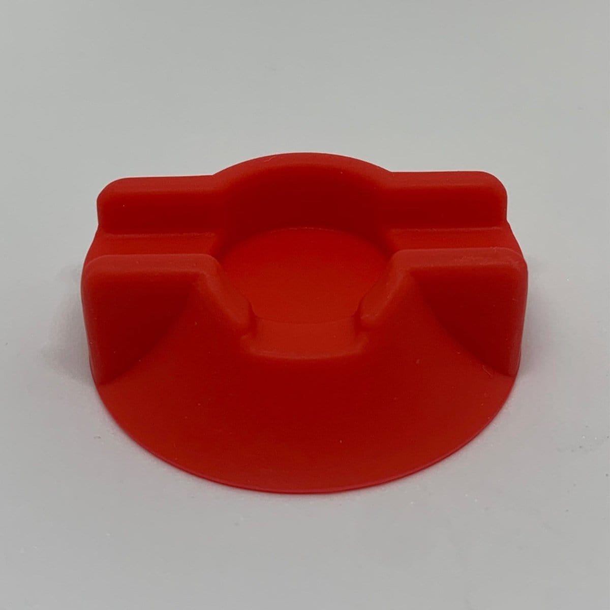A top-down view of the V2 Dabber Dock ® showing a curved, dark-colored holder on a white surface.