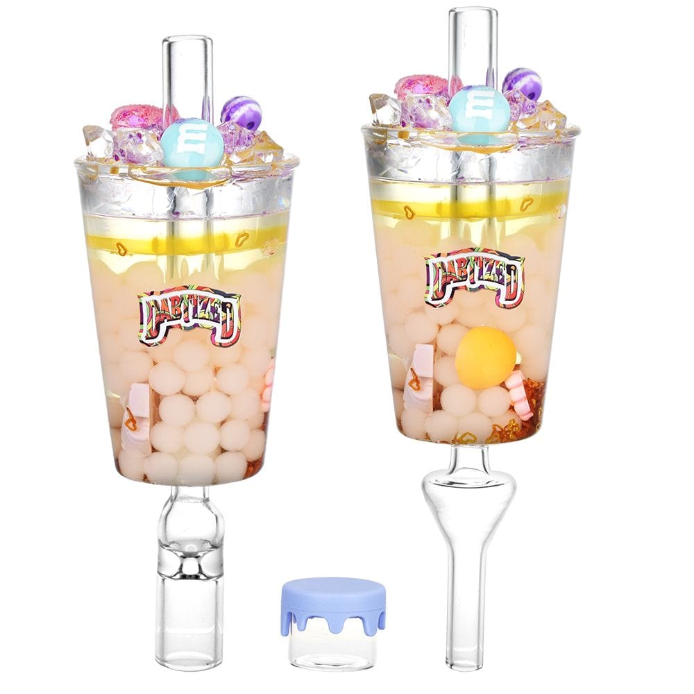 A slightly angled view of the Dabtized Bottoms Up Shot Glass 2 In 1 Honey Straw, showcasing its clear glass construction.