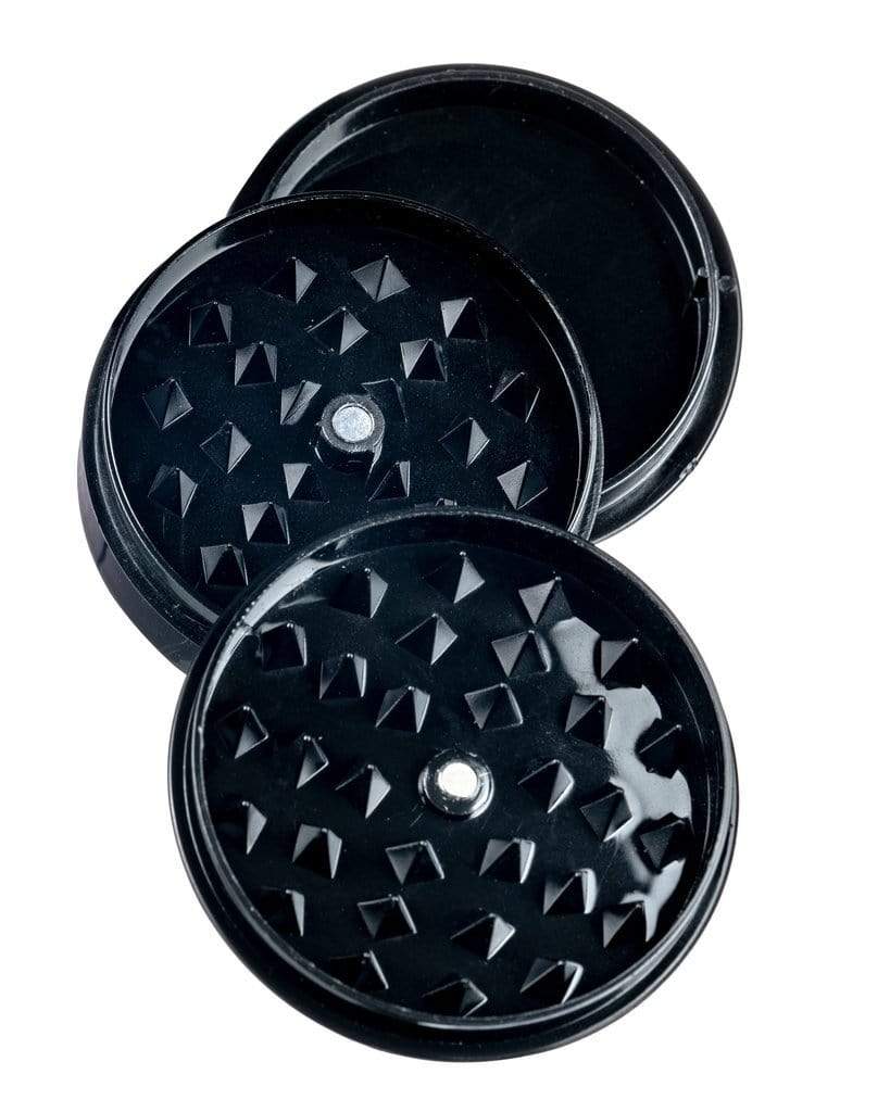 Front view of the Travel Herb Grinder & Stash Jar, a black, circular container with a textured top surface, angled against a plain white backdrop.