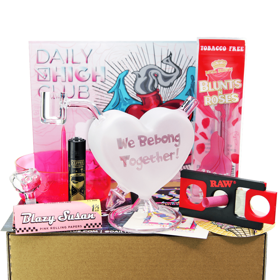 The “Love to Sesh” Smoking Box is pictured from the front, surrounded by colorful smoking accessories and resting on a brown surface.