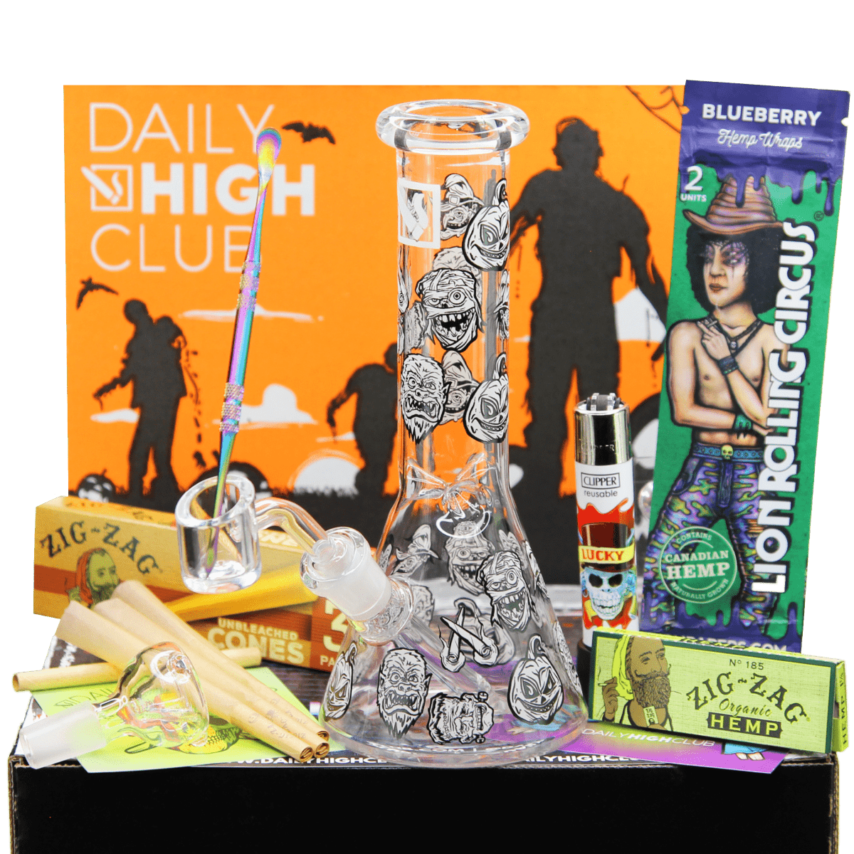 The “Monster Mash” Smoking Box is displayed in a still life with rolling papers and a lighter beside a glass piece, all on a patterned surface.