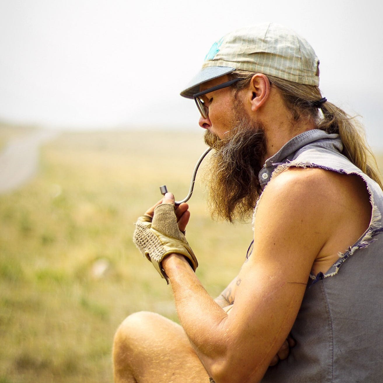A side view shows a person holding the WizardStix Titanium Wizard Pipe against a blurred, grassy background.