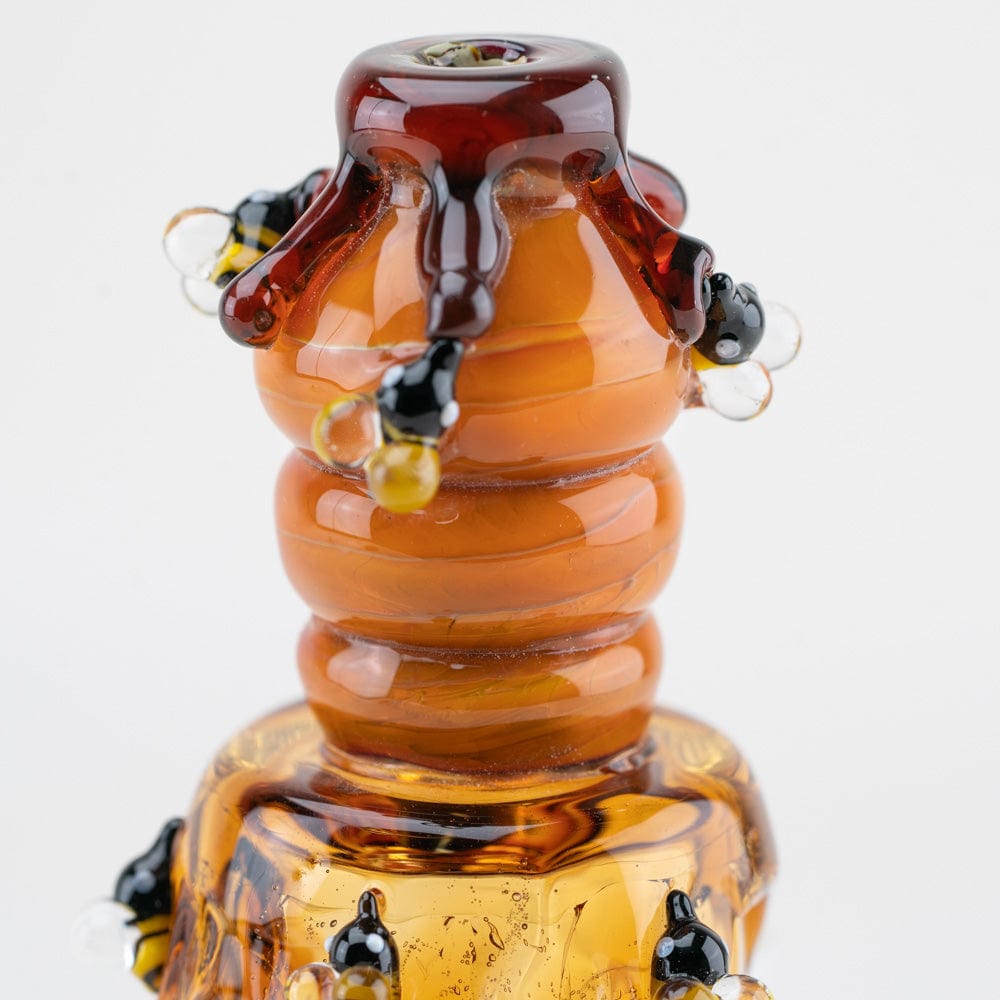 A close-up, angled view of the Beehive Nano Rig, showcasing its amber glass and sculpted, beehive-like form.