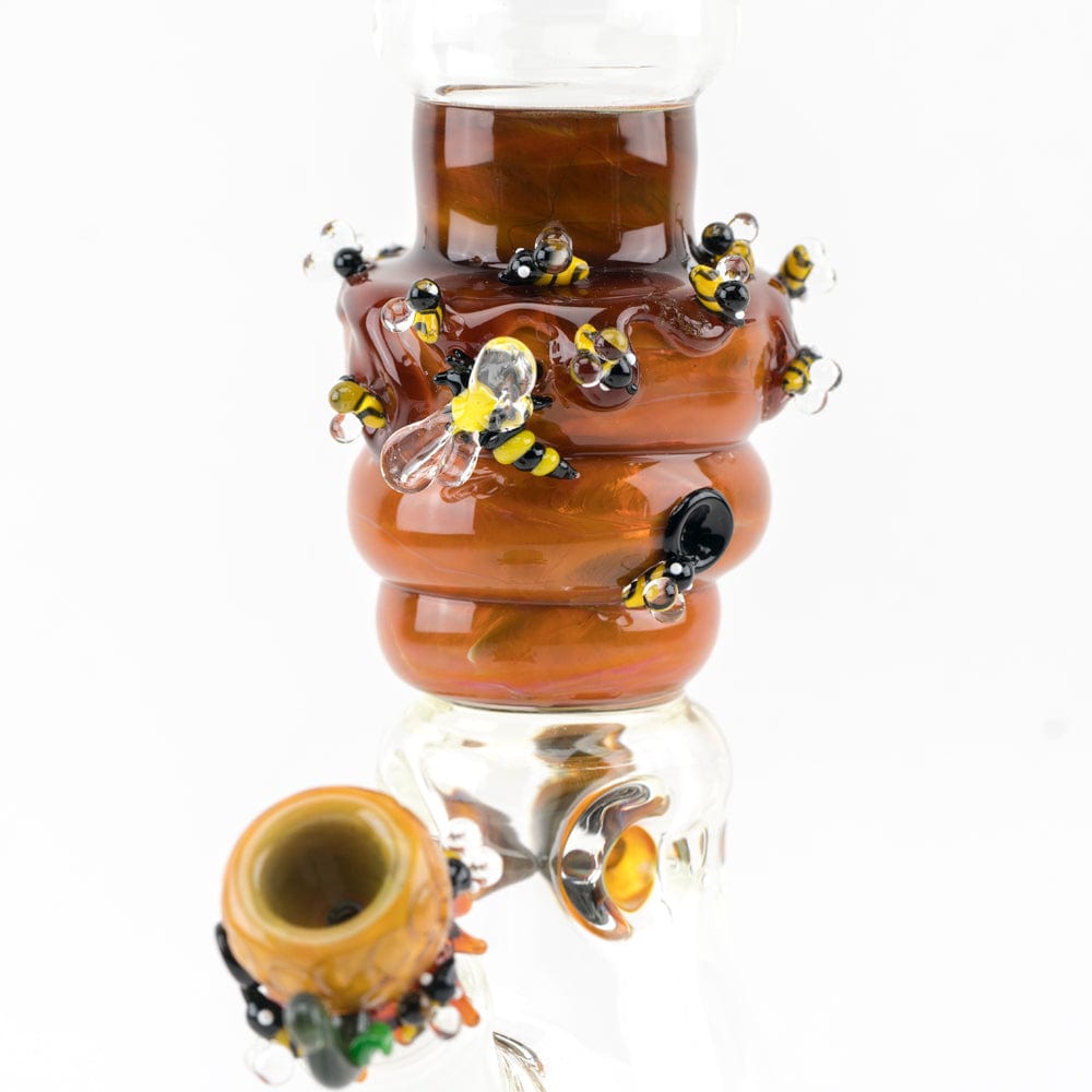A close-up, angled view of the Save the Bee's Beaker, showcasing decorative bee charms around the amber-colored glass chamber.