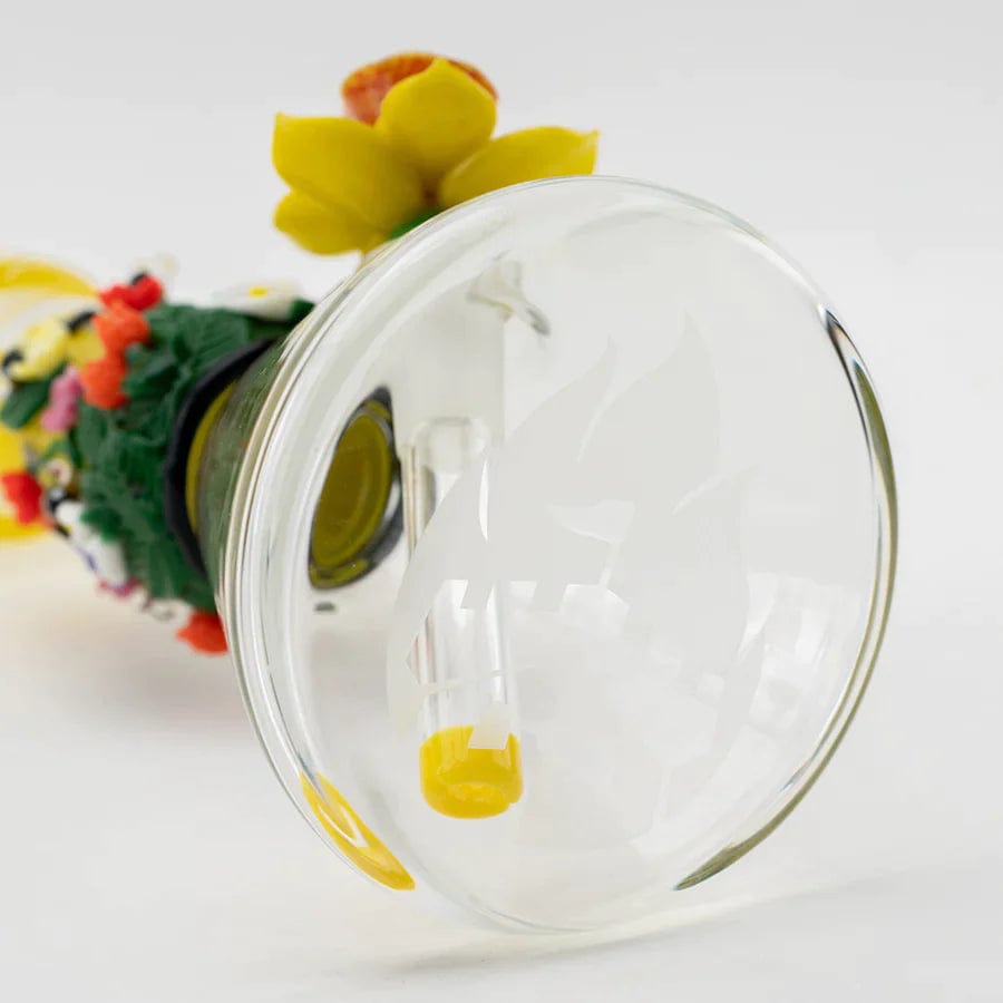 A close-up, angled view of the Sunshine Garden Beaker Water Pipe, showcasing its clear glass construction and decorative floral embellishment.